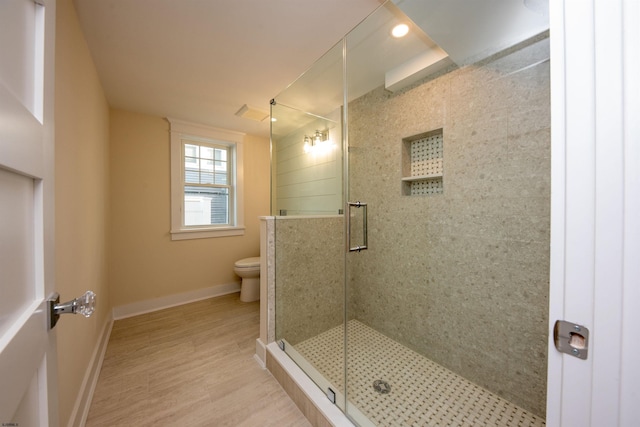 full bathroom featuring toilet, a stall shower, baseboards, and wood finished floors