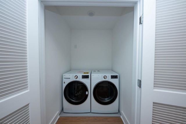 laundry room with laundry area, baseboards, washer and dryer, and wood finished floors