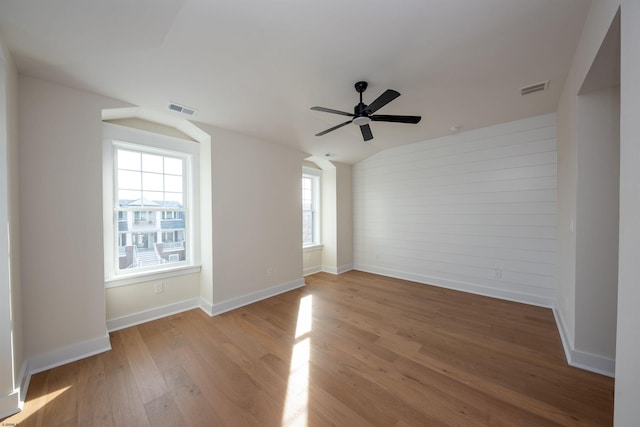 empty room featuring vaulted ceiling, wood finished floors, visible vents, and baseboards