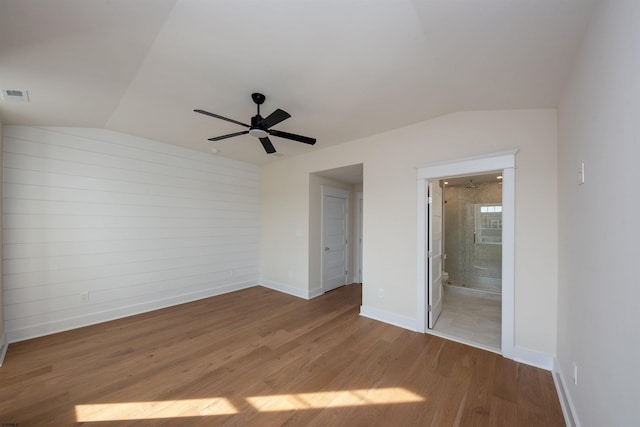 unfurnished bedroom with visible vents, vaulted ceiling, baseboards, and wood finished floors