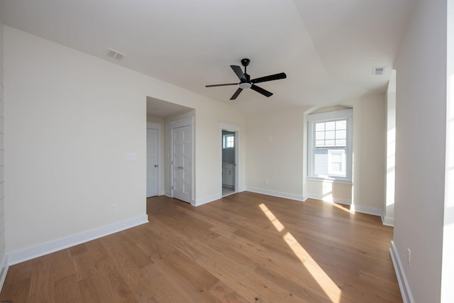 unfurnished room with a ceiling fan, visible vents, baseboards, and wood finished floors