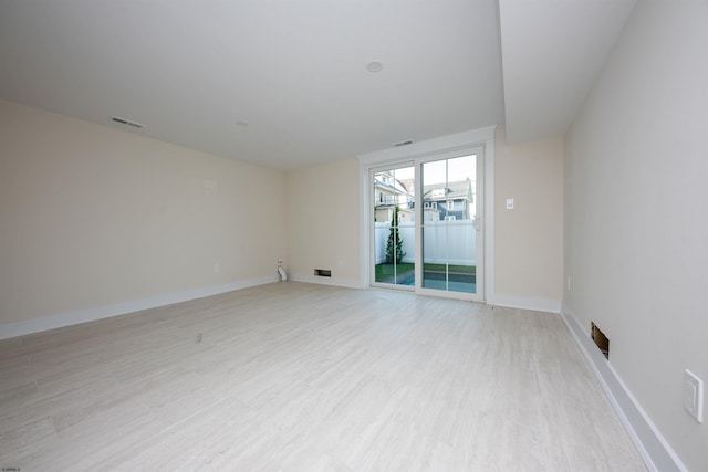 empty room with light wood-type flooring, visible vents, and baseboards