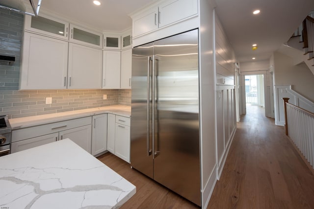 kitchen with white cabinets, glass insert cabinets, wood finished floors, backsplash, and built in fridge