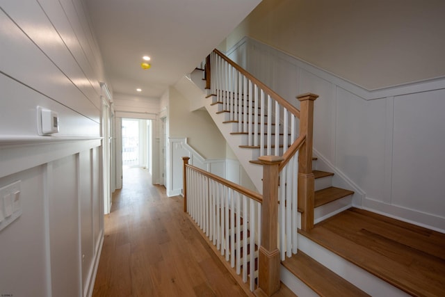 staircase featuring a decorative wall, wood finished floors, and recessed lighting