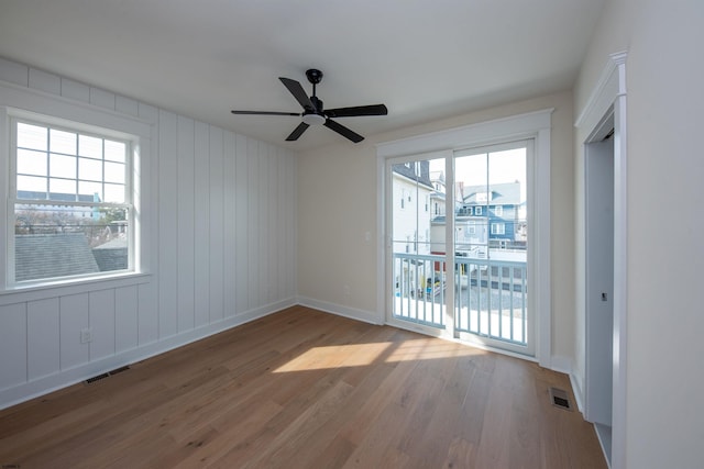 empty room featuring a healthy amount of sunlight, visible vents, and wood finished floors