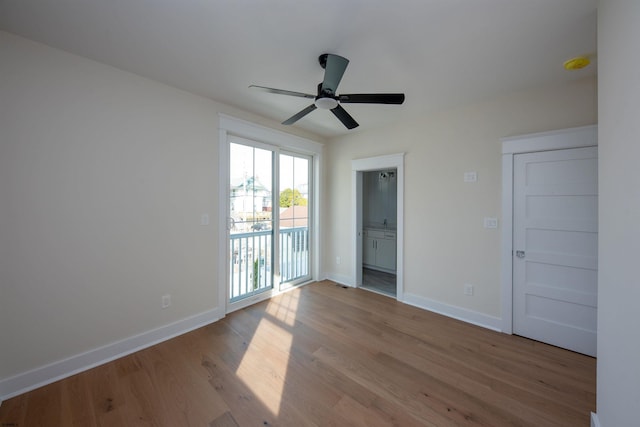 empty room with wood finished floors, a ceiling fan, and baseboards