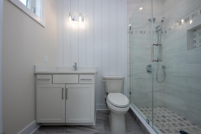 full bathroom with a stall shower, baseboards, vanity, and toilet