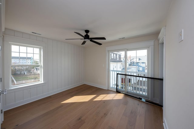 spare room featuring visible vents, ceiling fan, baseboards, and wood finished floors