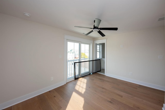 empty room with visible vents, ceiling fan, baseboards, and wood finished floors