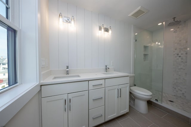 full bathroom with toilet, a stall shower, a sink, and visible vents