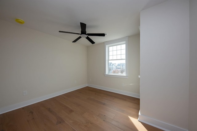 spare room featuring wood finished floors, a ceiling fan, and baseboards