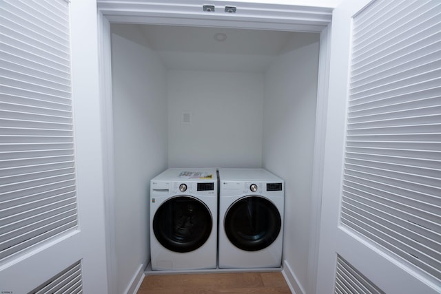 laundry room featuring laundry area, wood finished floors, and washing machine and clothes dryer