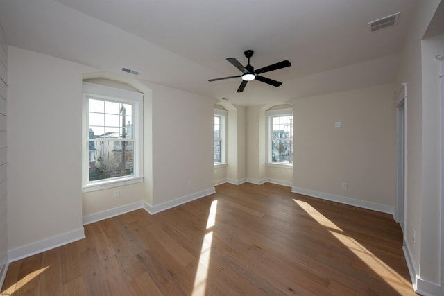 empty room featuring baseboards, visible vents, ceiling fan, and wood finished floors