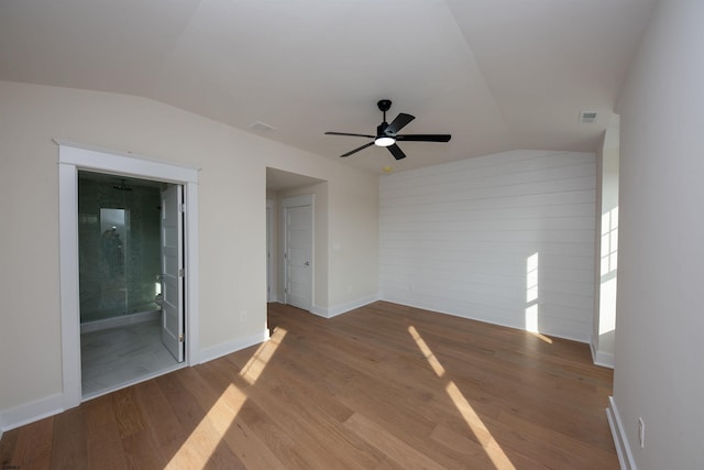 unfurnished room with lofted ceiling, visible vents, baseboards, and wood finished floors