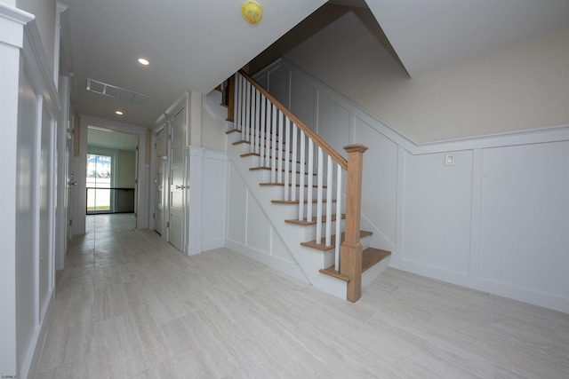 staircase featuring recessed lighting, visible vents, and a decorative wall