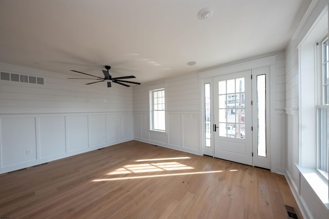 entryway featuring a decorative wall, a ceiling fan, visible vents, and light wood-style floors