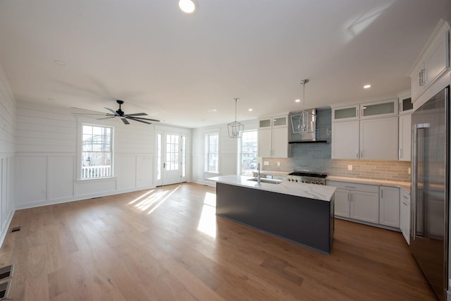 kitchen with range, decorative backsplash, a decorative wall, a sink, and built in fridge