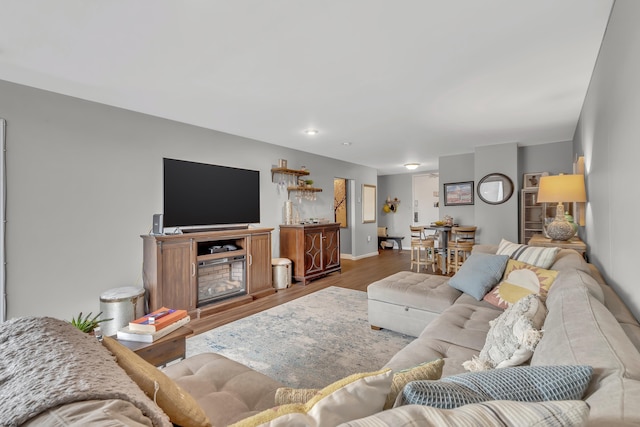 living area featuring a fireplace, baseboards, and wood finished floors