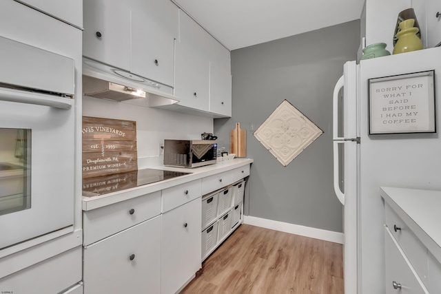 kitchen with light countertops, light wood-style flooring, white cabinets, white appliances, and under cabinet range hood