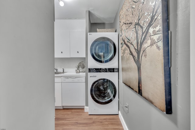 laundry area featuring a sink, stacked washer and dryer, and light wood-style floors