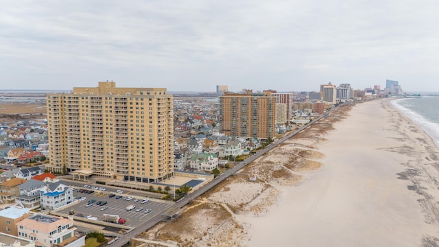 drone / aerial view featuring a water view, a view of city, and a beach view