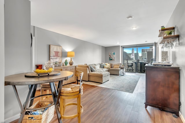 living area featuring light wood-style floors, a view of city, and a wall of windows