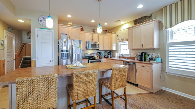 kitchen with stainless steel appliances, recessed lighting, a sink, and a breakfast bar