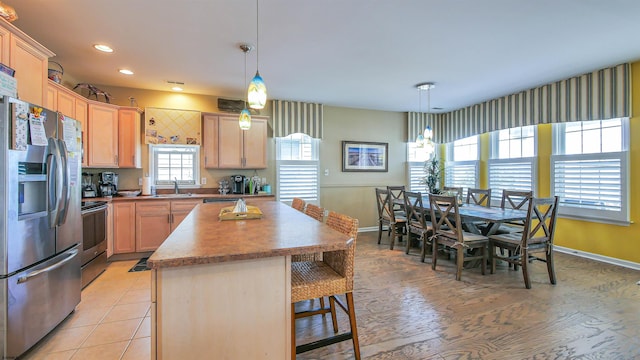 kitchen with recessed lighting, a sink, baseboards, appliances with stainless steel finishes, and a center island