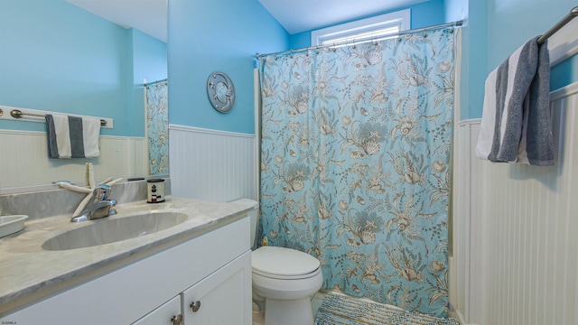 bathroom featuring toilet, a wainscoted wall, a shower with shower curtain, and vanity