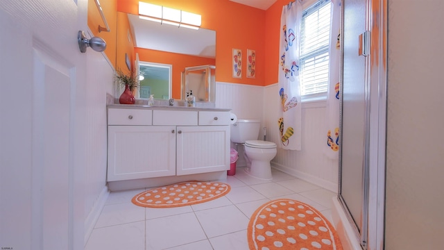 full bathroom with tile patterned flooring, toilet, vanity, wainscoting, and a stall shower