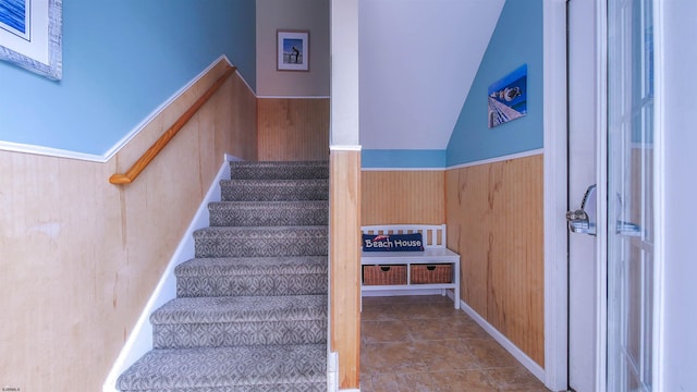 stairs featuring a wainscoted wall, tile patterned floors, and wood walls