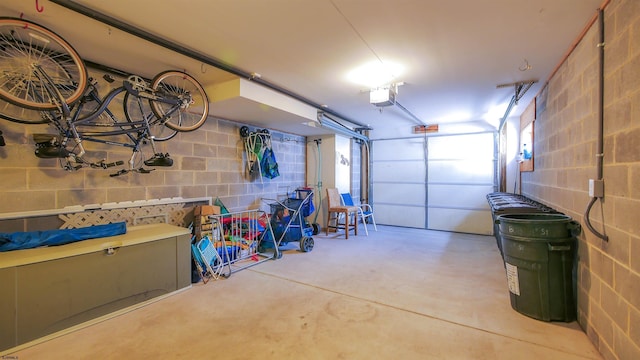 garage featuring a garage door opener and concrete block wall