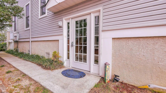 entrance to property featuring crawl space and stucco siding