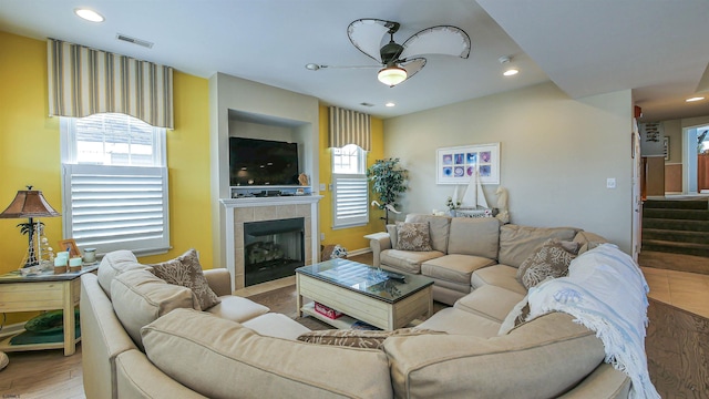 living area with visible vents, a tile fireplace, stairway, wood finished floors, and recessed lighting