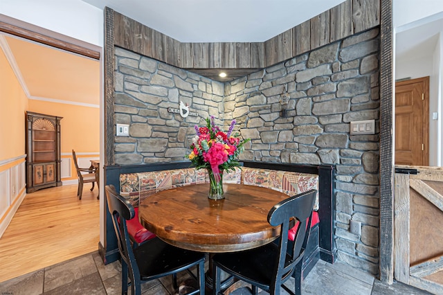 dining area with ornamental molding, wainscoting, and stone tile floors