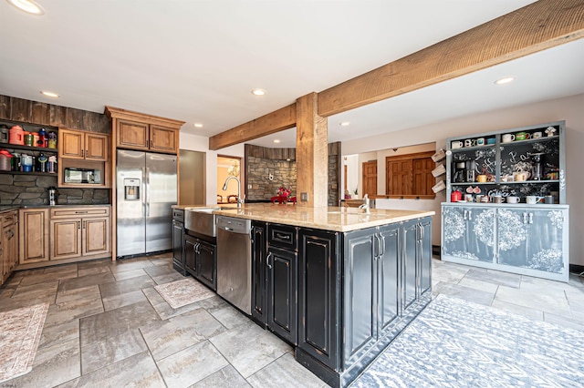 kitchen with appliances with stainless steel finishes, a sink, stone tile floors, and tasteful backsplash