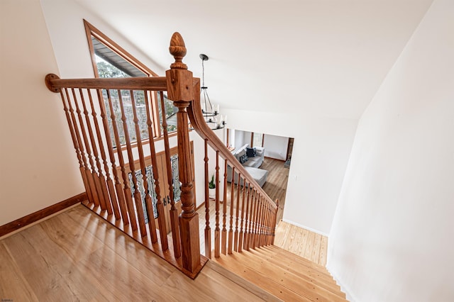 stairway featuring lofted ceiling, baseboards, and wood finished floors