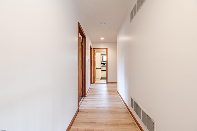 hallway with light wood-style flooring, recessed lighting, visible vents, and baseboards