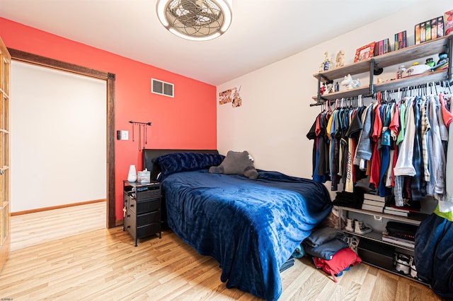 bedroom with wood finished floors, visible vents, and baseboards