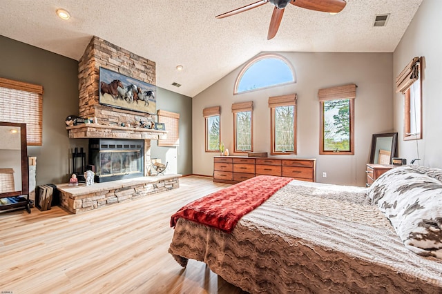 bedroom with lofted ceiling, a fireplace, visible vents, and wood finished floors