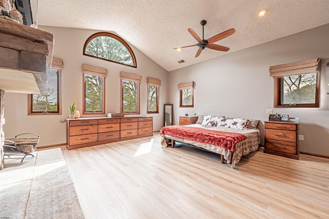 bedroom with light wood finished floors, baseboards, a ceiling fan, lofted ceiling, and a textured ceiling