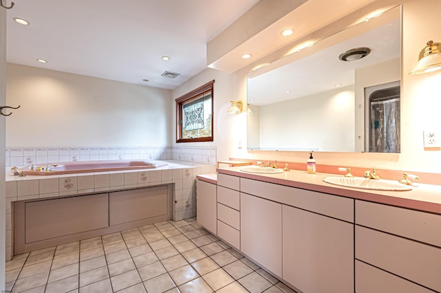 bathroom with a bath, a sink, visible vents, and tile patterned floors