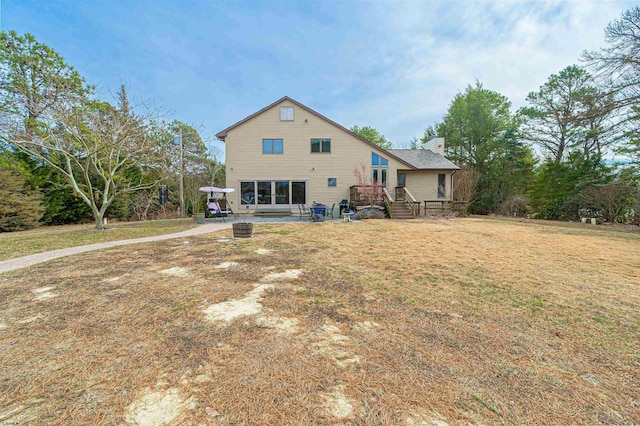 back of house featuring an outdoor fire pit, a patio area, a lawn, and a chimney