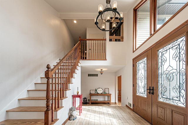 foyer entrance featuring a notable chandelier, a high ceiling, visible vents, stairs, and french doors