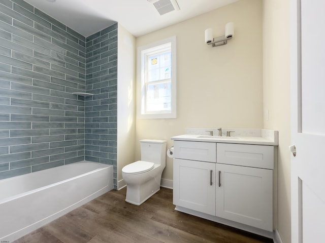 bathroom featuring toilet, wood finished floors, visible vents, vanity, and shower / washtub combination