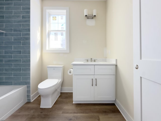 bathroom with vanity, wood finished floors, toilet, and baseboards