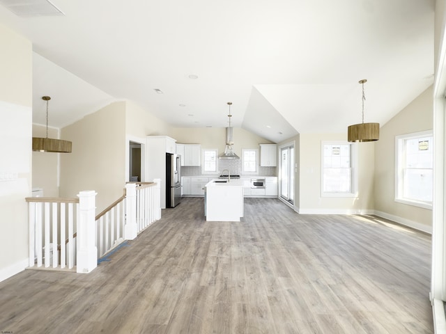 kitchen featuring lofted ceiling, wall chimney exhaust hood, high quality fridge, open floor plan, and light countertops