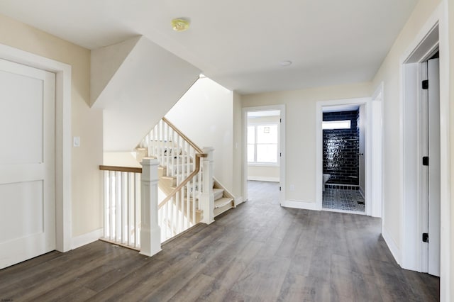 hall featuring baseboards, stairway, and wood finished floors