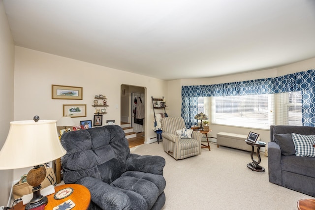 carpeted living room featuring a baseboard heating unit, arched walkways, and a baseboard radiator