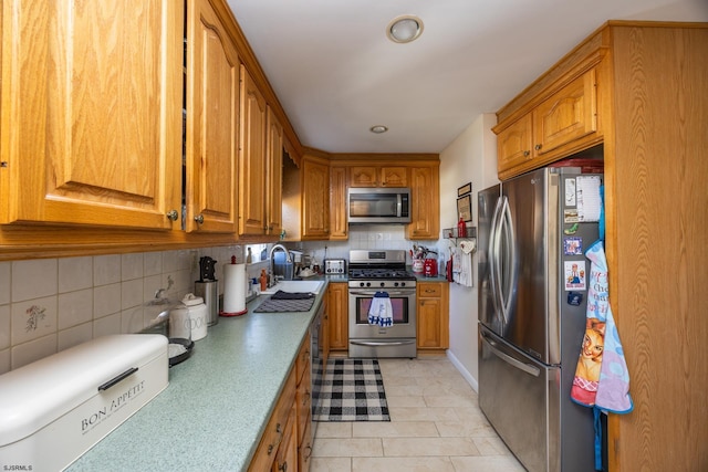 kitchen featuring appliances with stainless steel finishes, brown cabinets, a sink, and backsplash